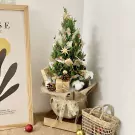 Decorated mini pine tree with pinecones, gifts, and stars.