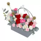 A grey rectangular flower basket with white and pink roses, red and pink carnations, and eucalyptus.
