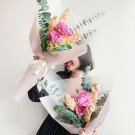 Woman holding two pastel bouquets of roses, hydrangeas, and filler flowers.