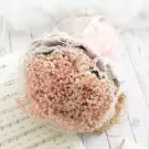 A bouquet of pink baby's breath flowers with lace and ribbon, resting on sheet music.