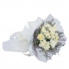 White carnation bouquet with purple filler flowers wrapped in white paper.