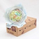 Pastel hydrangea bouquet in light blue wrapping sits atop a floral-decorated delivery box.