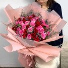 Buket mawar merah dan pink yang dibungkus kertas krep merah muda.