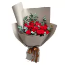 Bouquet of red roses and eucalyptus leaves wrapped in taupe paper with a brown ribbon.