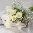 White tulips and baby's breath bouquet on a book.