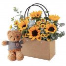 Teddy bear with bouquet of sunflowers in a gift bag.