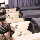 Hair salon washing stations with reclining chairs and stools.
