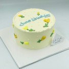 Yellow cake with blue "Sweet Birthday" lettering and yellow tulip decorations.