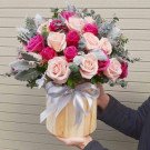 A wooden round box filled with pink and magenta roses, accented with dusty miller leaves and a silver ribbon.