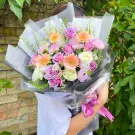 A lush bouquet of pink, purple, and white roses, gerbera daisies, and carnations.
