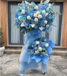 Large blue and white flower arrangement with hydrangeas, roses, and calla lilies on a stand.