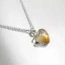 Silver necklace with a heart-shaped, translucent amber-colored stone.