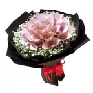 Money bouquet made of folded pink bills and baby's breath, wrapped in black paper with a red ribbon.
