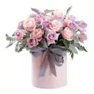 Round pink hatbox with pastel and lavender roses and a grey ribbon.