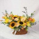 Basket of sunflowers, roses, carnations, and gerbera daisies in warm yellow and orange tones.