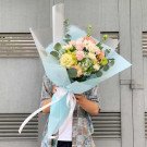 Bouquet with pink, yellow, white, and green flowers, wrapped in light blue paper with a white ribbon.