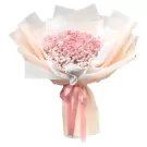 Pink baby's breath flowers wrapped in pale pink and white paper with a pink ribbon.