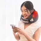 Woman smiling, wearing a neck massager and looking at her phone.