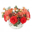 Red roses, orange carnations, and red berries in a clear glass vase.