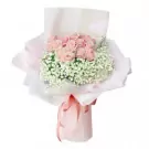 Pink roses and baby's breath bouquet wrapped in light pink paper, tied with a pink ribbon.