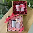 Gift set with two boxes of roses, candles, and perfume bottles.