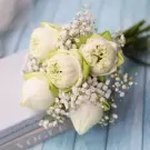 White lotus bouquet with baby's breath on a book and blue wooden surface.