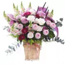 Pink and purple flowers in a wooden box with a pink ribbon.