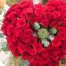 Heart-shaped arrangement of 99 red roses, succulents, and eucalyptus.