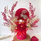 Maneki-neko cat with red berries, gold leaves, and a red peony in a pink box.