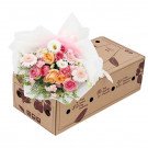 A bouquet of pink and orange roses, gerberas, and eustoma in a gift box.