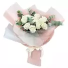 Bouquet of white roses and eucalyptus leaves, wrapped in pink and white paper with a ribbon.