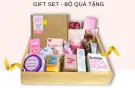 Gift set with bath bomb, body scrub, soap, and rose petals in a wooden crate.