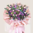 A glamorous flower stand with purple and cream roses, hydrangeas, and eucalyptus.
