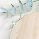 Silver ring with two moonstones in a delicate branch design, resting on wood.