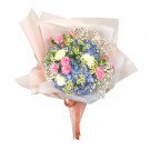 Bouquet of blue hydrangeas, pink carnations, white roses, and baby's breath, wrapped in pink paper.