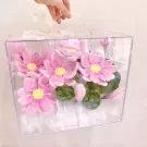Clear box with pink lotus flowers and green pods, held by a hand.