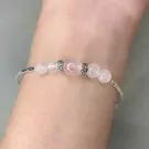 Ethereal Bloom bracelet with rose quartz and silver charms on a wrist.