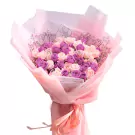 Pink and purple rose bouquet wrapped in pink paper, tied with a pink ribbon.