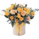 Yellow and peach roses in a light wood box with yellow ribbon.