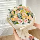 Bouquet of pink, peach, and cream roses with small white flowers and eucalyptus.