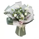 White roses, hydrangeas, and blue filler flowers with eucalyptus in a pale green and white bouquet.