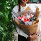 Woman holding a bouquet of pink roses wrapped in brown paper with "Gorgeous You" text.