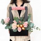 Pink roses and Ferrero Rocher chocolates in a black gift box with pink ribbon handle.