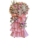 A tiered arrangement of pink and white flowers with delicate pink accents, presented on a stand.