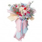 Bouquet of pink and red roses, carnations, daisies, hydrangeas, delphiniums, and baby's breath in pastel and red wrappers.