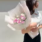 Woman holding a pastel pink and white rose bouquet.