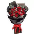 A bouquet of 36 red roses wrapped in black paper with a red ribbon.
