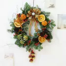 Christmas wreath with dried oranges, pinecones, berries, and ribbon bow.