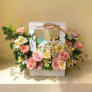 Pink and white flowers in a basket with a blue butterfly and gold ribbon.