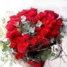 Bouquet of 99 red roses, succulents, and greenery in a square box.